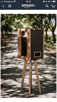 a wooden camera stand on the side of a road with trees in the back ground