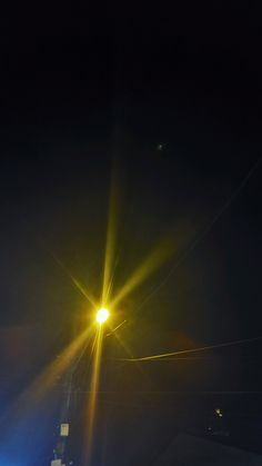 the street light is shining brightly in the dark night sky with no one around it