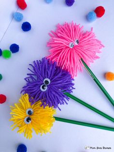 three colorful pom poms with eyes on them