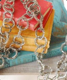 a stack of books sitting on top of a table next to a chain link bracelet