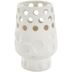 a white vase with holes in the middle and circles on it's side,