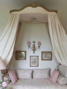 a canopy bed in a bedroom with pink and white decor on the wall above it