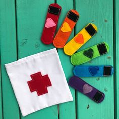 several colorful socks with hearts and crosses on them sitting next to a white cloth bag