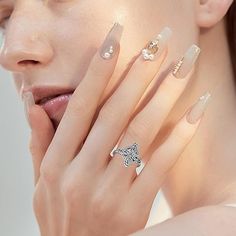 a woman with long nails holding her hand up to her face