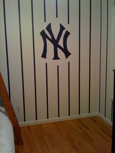 the new york yankees logo is painted on a wall in a room with striped walls