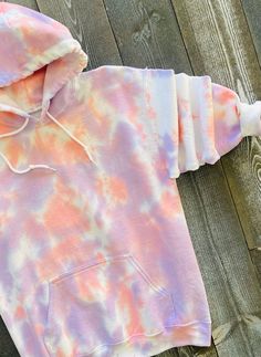 a pink and blue tie dye hoodie on a wooden surface