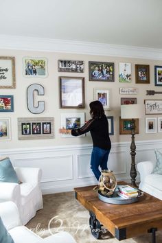 a woman is hanging pictures on the wall