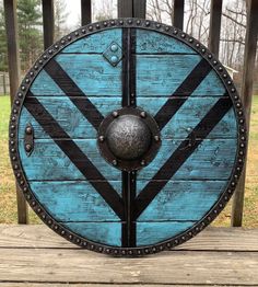 a blue and black shield sitting on top of a wooden table next to a fence