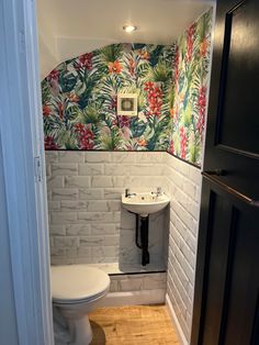 a bathroom with a toilet, sink and wallpaper on the walls in it's corner