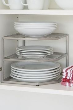 plates and bowls are stacked on the shelves in this kitchen cabinet, which is open to reveal dishes