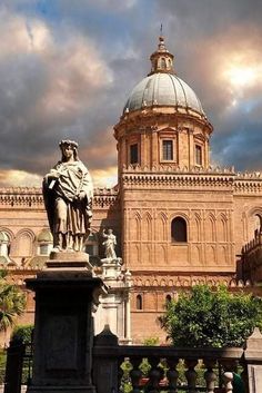 a statue in front of a large building with a dome on it's roof