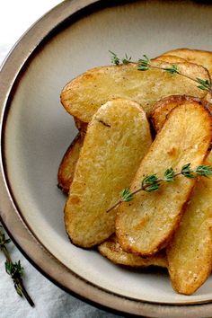 a white plate topped with fried potatoes covered in seasoning and sprinkled with herbs