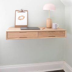 a desk with a laptop and lamp on it in a room that has white walls