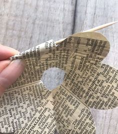 someone is holding an origami flower made out of old newspaper paper and knitting needles