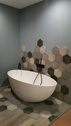 a large white bath tub sitting on top of a tiled floor next to a wall