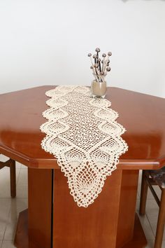 a wooden table topped with a white doily on top of a wooden dining room table