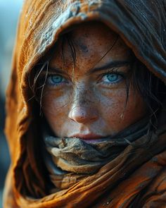 a woman with freckled hair and blue eyes wearing a brown scarf over her head