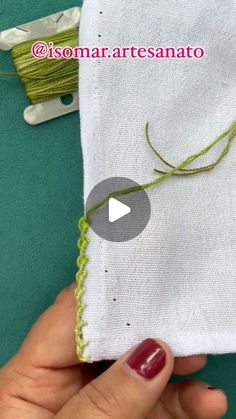 someone is stitching on the side of a piece of fabric with green thread and scissors