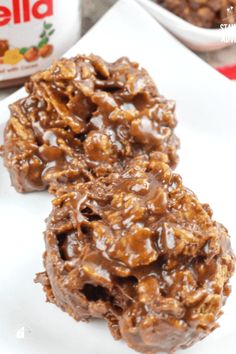 two chocolate cookies on a white plate with yogurt in the backgroud