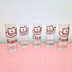 three shot glasses sitting on top of a pink table next to each other, with the same logo