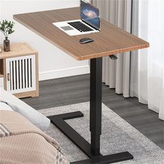 a laptop computer sitting on top of a wooden desk next to a bed in a room