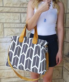 a woman is holding a handbag in front of a brick wall