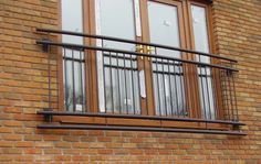 a brick building with a metal balcony and window sill on the outside, next to a bench in front of it