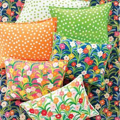 colorful pillows are stacked on top of each other in different colors and patterns, with polka dots