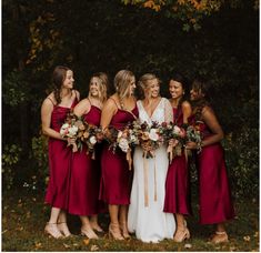 a group of women standing next to each other in front of trees with flowers on them