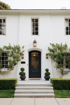 a white house with black front door and steps leading up to the entryway area