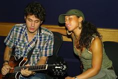 a man and woman sitting next to each other playing guitars