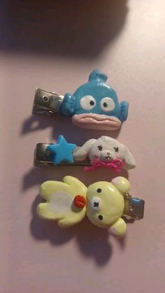 three little cartoon hair clips on top of a table