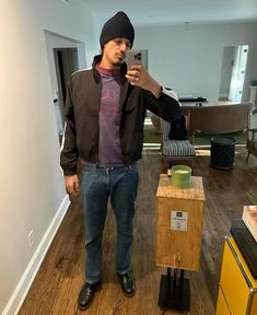 a man taking a selfie with his cell phone in a living room next to a box