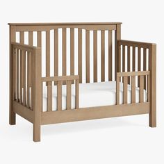 a wooden crib with white sheets on it