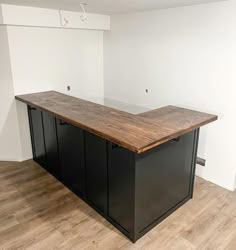 an empty room with two black cabinets and a wooden counter top in the middle of it