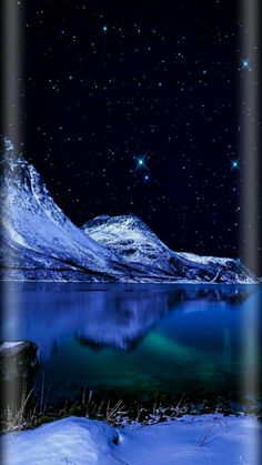 the stars are shining in the night sky over a mountain lake and snow covered mountains