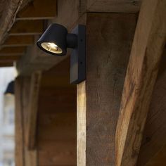 an outdoor wall light on the side of a building with wood planks and beams