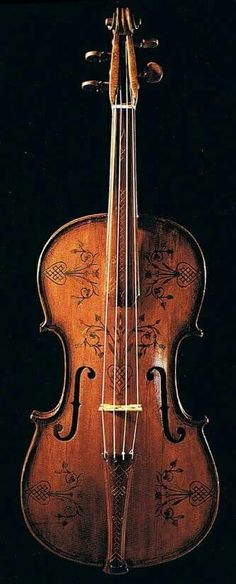 an old violin sitting on top of a black surface with the strings still attached to it