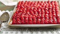 a close up of a pan of food with strawberries on the top and spoon next to it