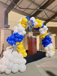 an arch made out of balloons and starbursts is displayed in front of a podium