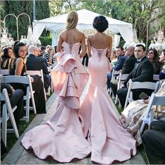 two women in pink dresses walking down the aisle