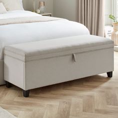 a bed with a white blanket on top of it and a wooden floor next to it