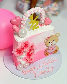 a pink and white birthday cake sitting on top of a table