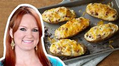 a woman with red hair and blue shirt next to baked potatoes on a baking sheet