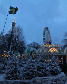 a ferris wheel and christmas trees in front of a building