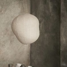 a table topped with plates and cups next to a white paper lantern hanging from the ceiling