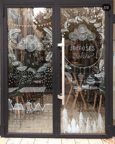 a store front window that has been decorated with christmas trees and snowflakes on it