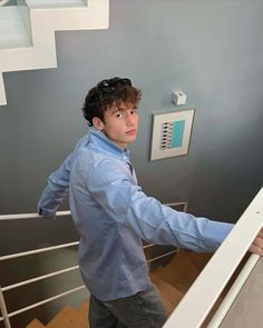 a young man is climbing the stairs in his house and looking at something on the wall