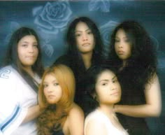 four beautiful young women posing together in front of a blue background