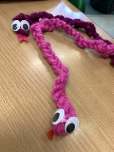 a pink rope with googly eyes on it sitting on top of a wooden table